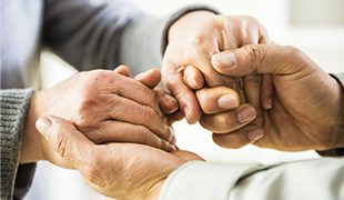 Hands reaching out between two people and clasping each other best funeral plans