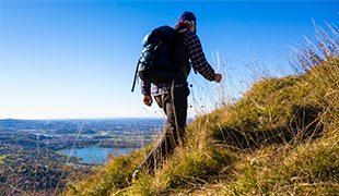 Man hiking up picturesque hillside with views funeral plans uk
