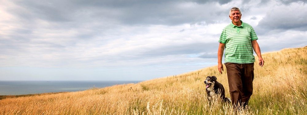 Man walking his dog in a field of long grass funeral plans