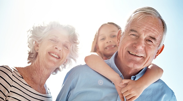 Grandparents looking happy, with granddad giving granddaughter a piggy back. Funeral Plans