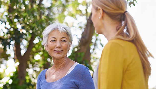 Senior woman chatting with another lady in a woodland funeral plans uk over 50