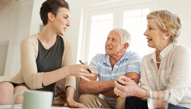 Senior couple taking advice from a young lady british seniors funeral plan